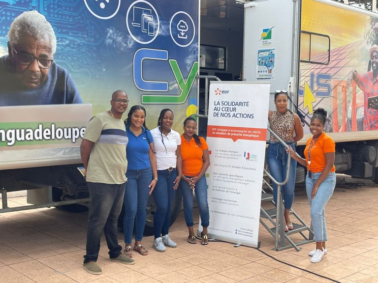 Photo d'un groupe de six personnes, dont des conseillers EDF, France Renov' et CCAS, posent devant un cyberbus aux couleurs de la Guadeloupe